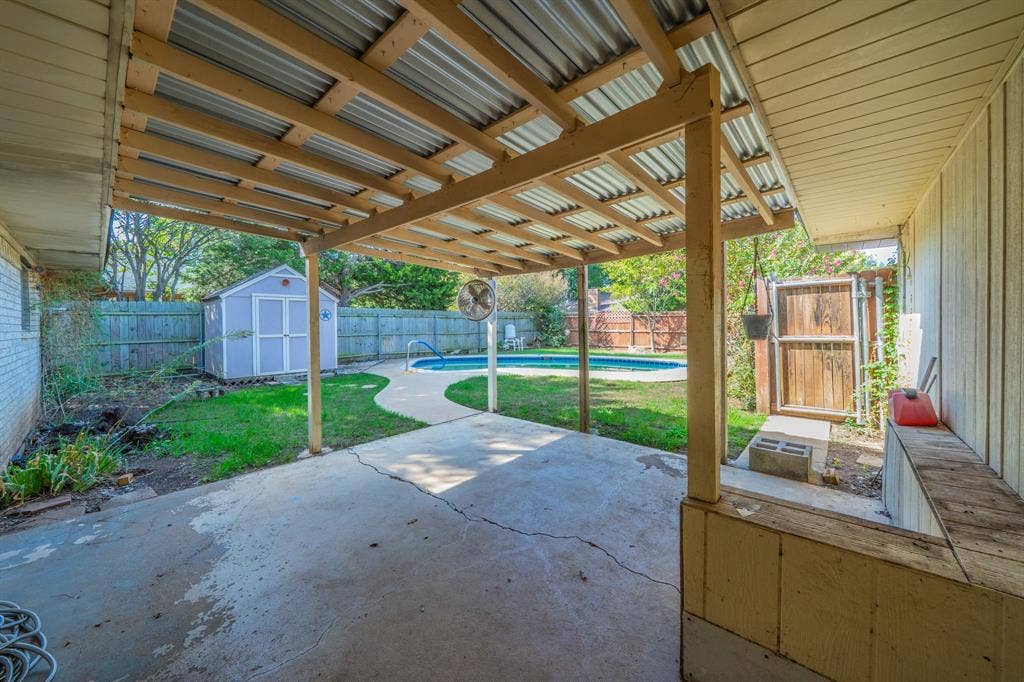 1517 Meadow Court, Midlothian, TX 76065 Covered patio with concrete flooring, wood privacy fencing, a storage shed, and an inground swimming pool