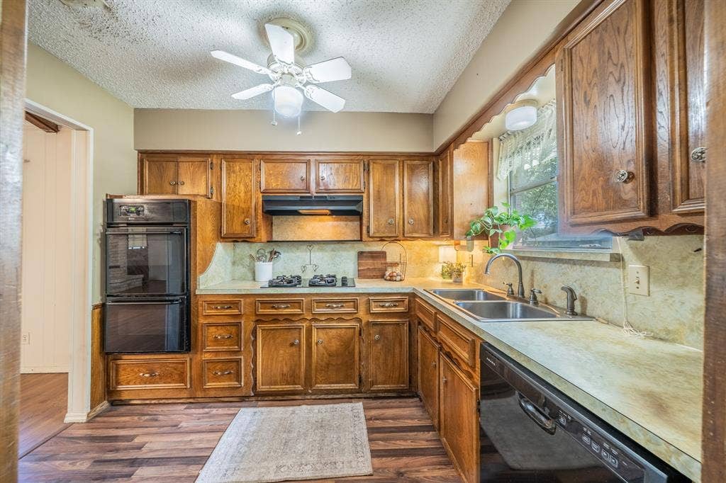 1517 Meadow Court, Midlothian, TX 76065 Wood-finish flooring, wood cabinetry, built-in double ovens, dual basin sink, and a ceiling fan with integrated lighting