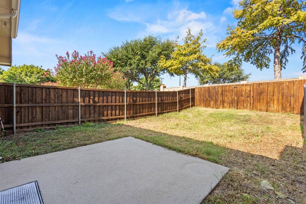 Spacious backyard with privacy fencing, mature trees, and a concrete patio