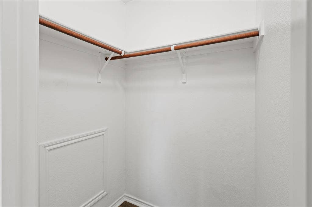 White-painted closet with wood-finish hanging rods and panel molding