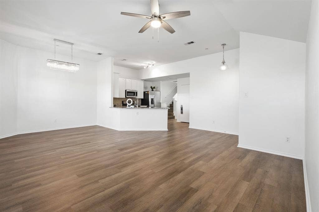 Open-concept living area featuring wood-finish flooring, a modern chandelier, and a ceiling fan