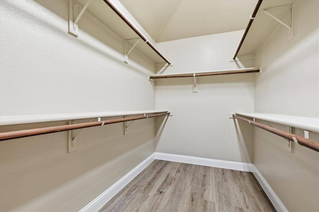 4516 Remuda Lane, Denton, TX 76226 Expansive walk-in closet featuring multiple shelving units, integrated hanging rods, and wood-finish flooring
