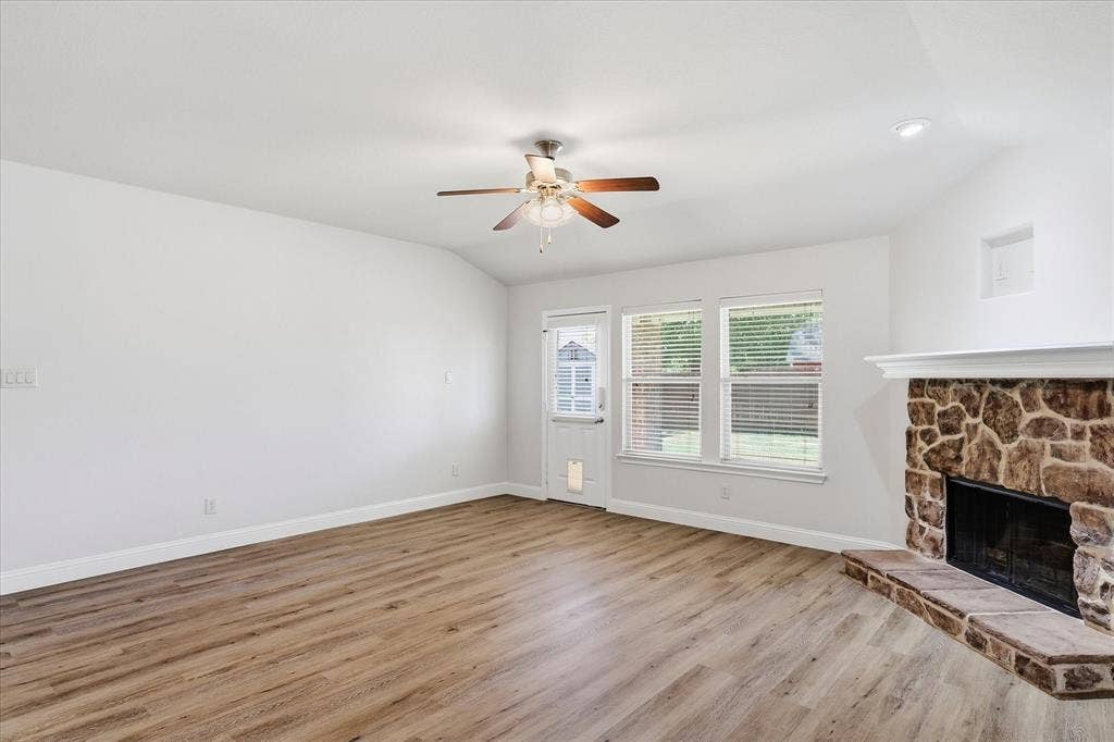 4516 Remuda Lane, Denton, TX 76226 Wood-finish flooring throughout, ceiling fan with light fixture, stone-faced fireplace with hearth, recessed lighting, and multiple windows