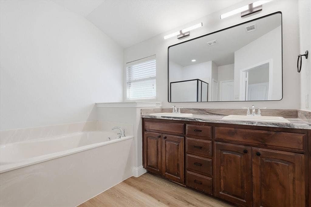 4516 Remuda Lane, Denton, TX 76226 Dual sink vanity with dark wood cabinetry and integrated sinks, complemented by a large rectangular mirror