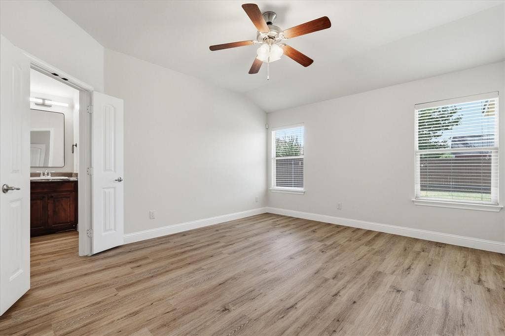 4516 Remuda Lane, Denton, TX 76226 Vaulted ceiling with a ceiling fan, wood-finish flooring, two windows with blinds, and white double doors