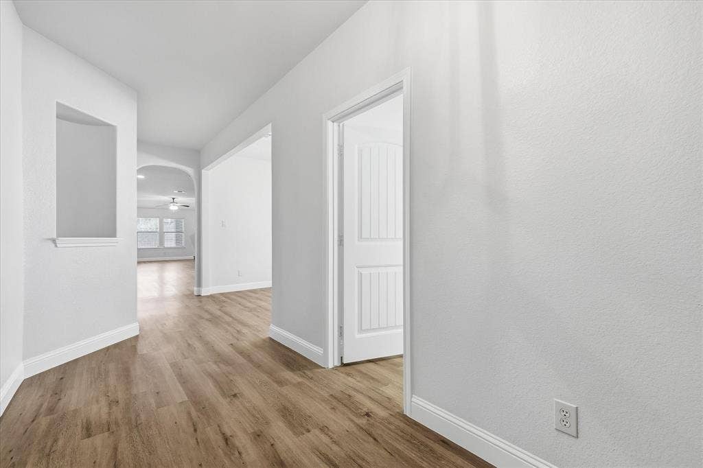 4516 Remuda Lane, Denton, TX 76226 Hallway with wood-finish flooring, an arched doorway, and a built-in wall niche