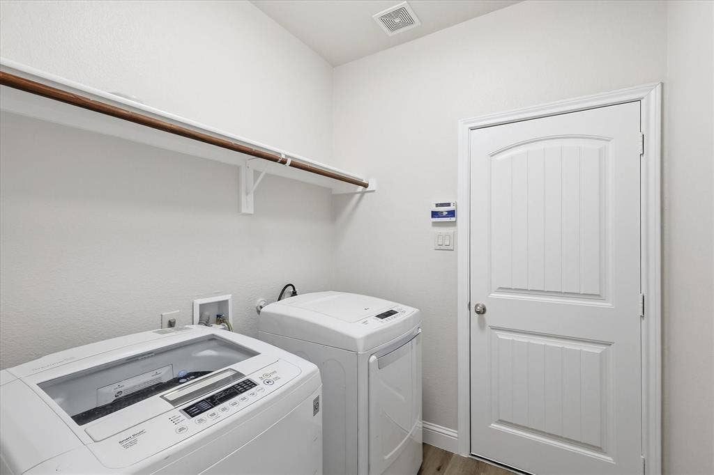 4516 Remuda Lane, Denton, TX 76226 Laundry area featuring a wall-mounted shelving unit with a hanging rod, a white paneled door with an arched top, and light-toned flooring