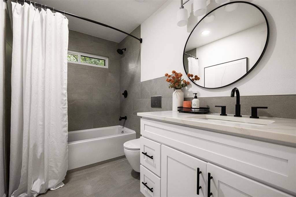 Bathroom featuring a white vanity with shaker-style cabinetry, matte black hardware, a rectangular undermount sink, and a light-toned countertop
