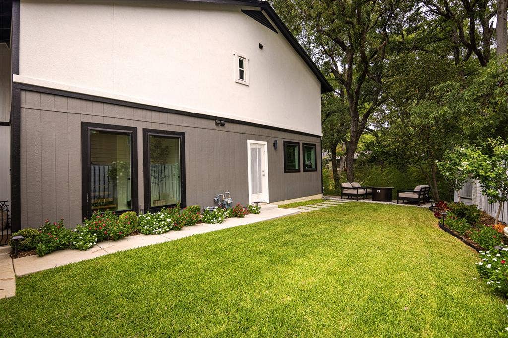Backyard featuring a lush lawn, established trees, stepping stone pathway, and mature landscaping