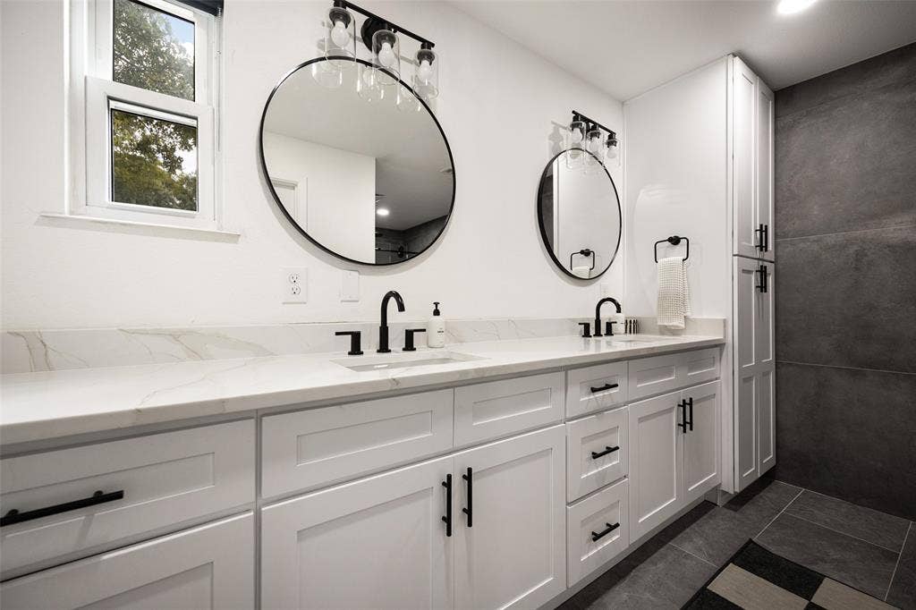 Dual vanity with white cabinetry, matte black hardware, and stone-finish countertops