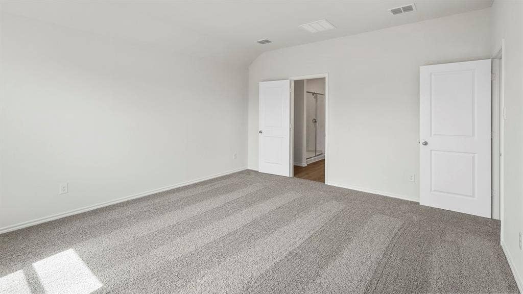 Spacious room featuring light gray carpeting, crisp white walls, and two white panel doors