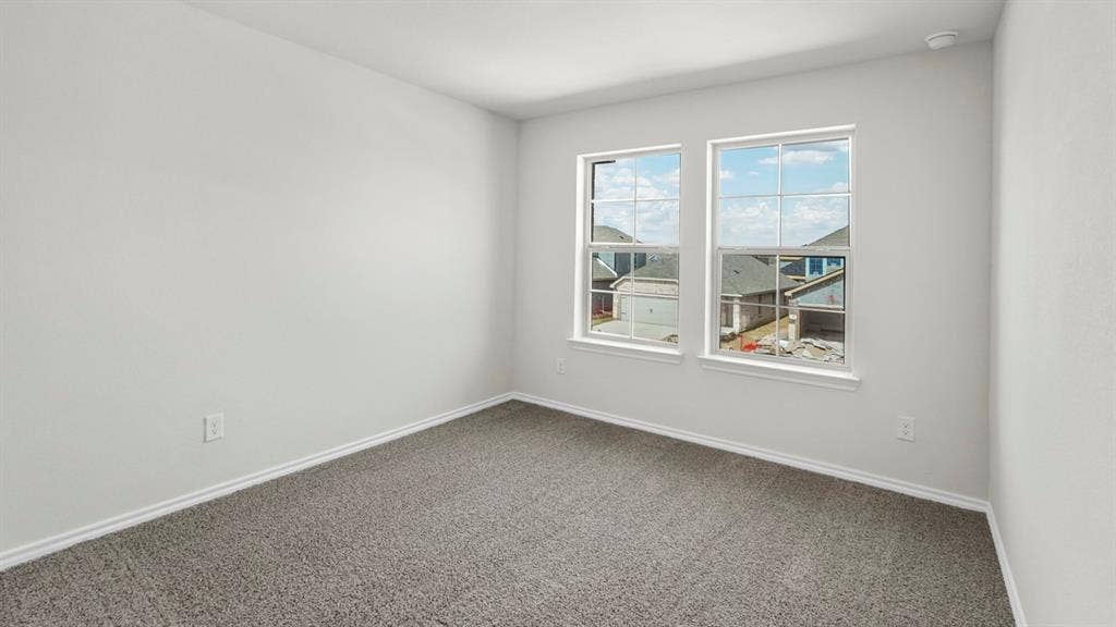 Room featuring two paneled windows, neutral wall paint, gray carpet flooring, and white baseboards