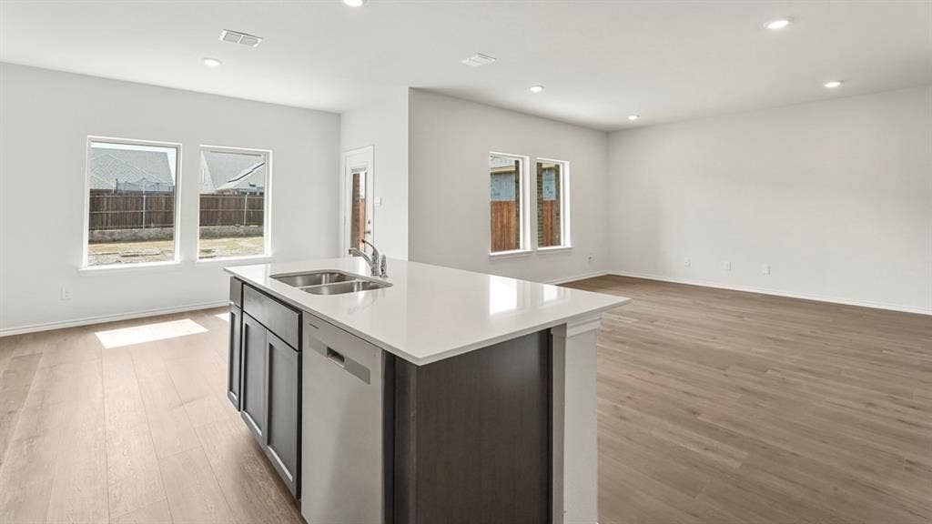 Kitchen island featuring a double-basin sink, stainless steel faucet, and integrated dishwasher