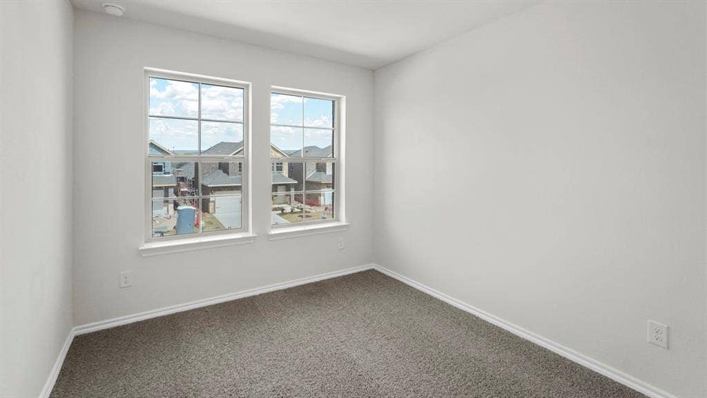 Bedroom featuring two windows, neutral gray carpeting, white baseboards, and light-colored wall paint