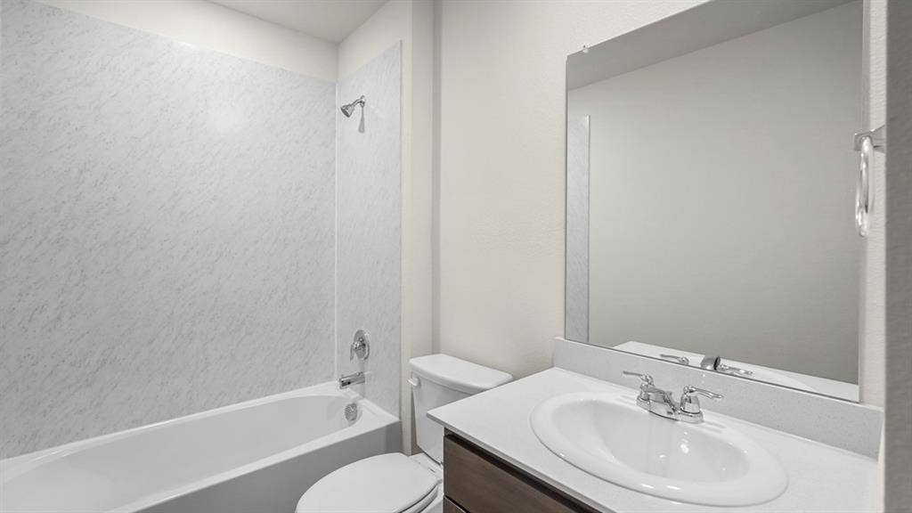 Bathroom featuring a white tub with a patterned shower surround, chrome fixtures, and a white toilet