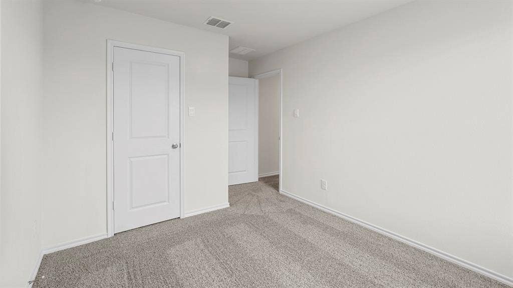 Interior room featuring light gray carpeting, white walls, white trim, and a white two-panel interior door with a brushed nickel knob