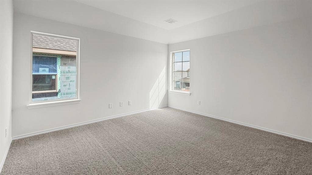 Spacious room featuring neutral grey carpeting, crisp white walls, and a recessed ceiling detail