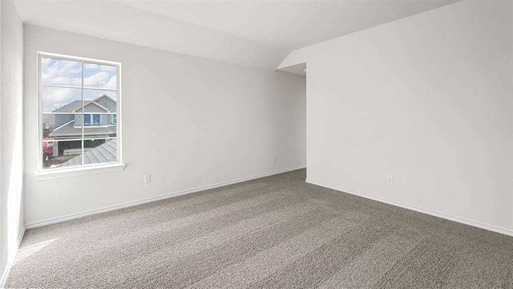 Spacious room featuring neutral carpeting, white wall finishes, and an expansive window with grid panes