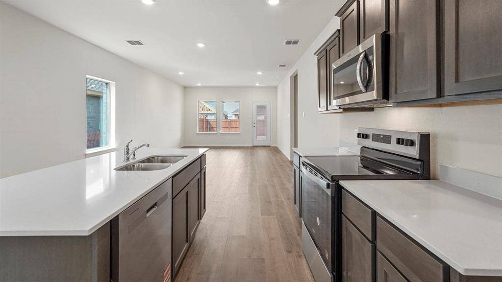 Kitchen featuring a large island with a double basin sink and stainless steel dishwasher