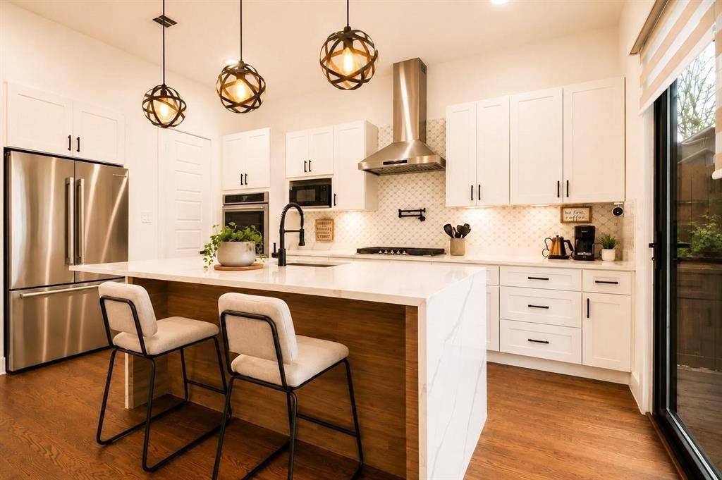 713 Wayne Street, Dallas, TX 75223 Kitchen featuring white cabinetry, stainless steel appliances, a center island with a waterfall countertop, pendant lighting, and wood-finish flooring