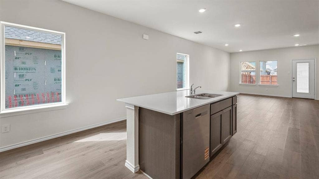 5606 Gannet Place, Crandall, TX 75114 Open-concept living area with wood-finish flooring, recessed lighting, and a kitchen island featuring a double sink, stainless steel dishwasher, and cabinet storage