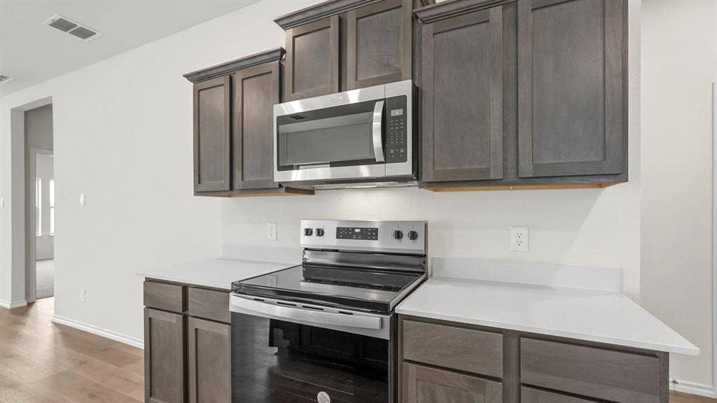 5606 Gannet Place, Crandall, TX 75114 Kitchen space featuring dark wood-finish cabinetry, light countertops, and a stainless steel range with an overhead microwave