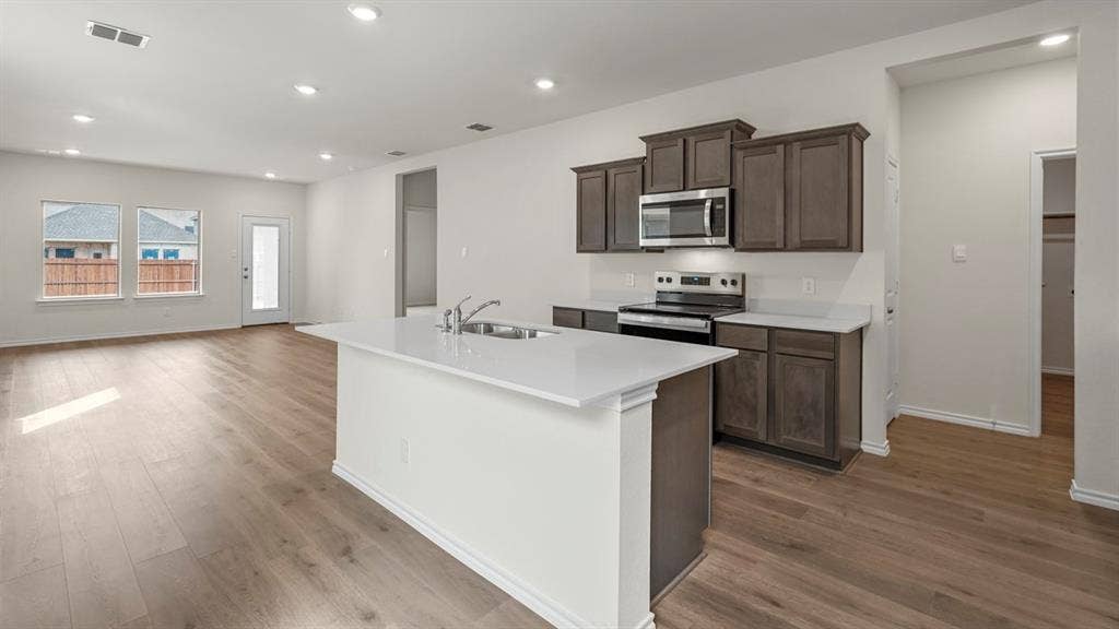 5606 Gannet Place, Crandall, TX 75114 Open-concept kitchen featuring an island with a sink, wood-finish flooring, recessed lighting, white countertops, and dark wood cabinetry