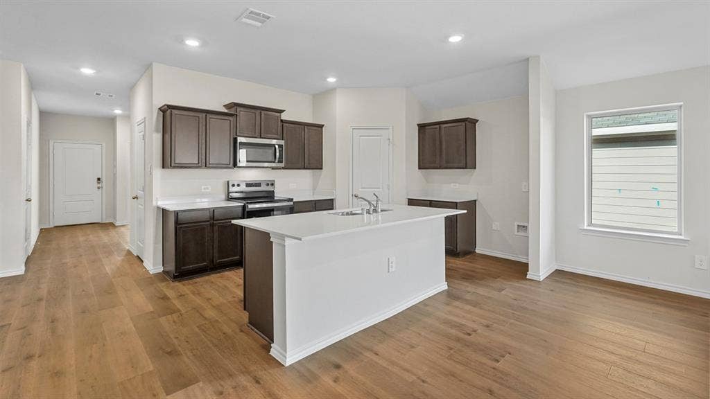 227 Whispering Pine Drive, Royse City, TX 75189 Kitchen featuring dark wood cabinetry, white countertops, stainless steel appliances, and a central island with an integrated sink