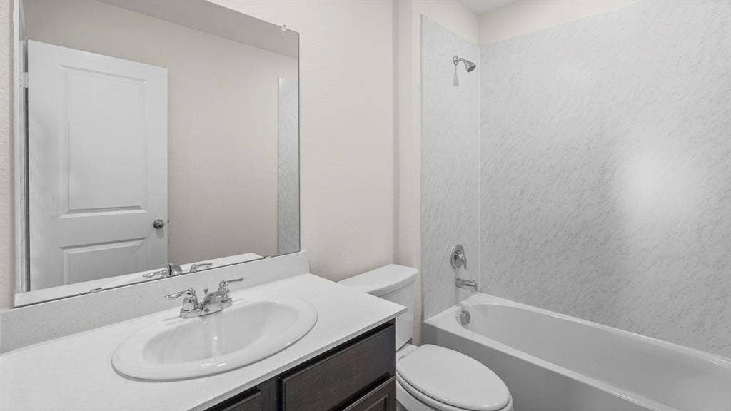 227 Whispering Pine Drive, Royse City, TX 75189 Bathroom featuring a vanity with an integrated sink, polished chrome faucet, full-width mirror, and a tub-shower combination with a textured surround