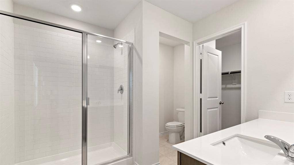 223 Yates Street, Bullard, TX 75757 Shower enclosure with sliding glass doors, subway tile surround, vanity with an integrated sink, and a separate water closet