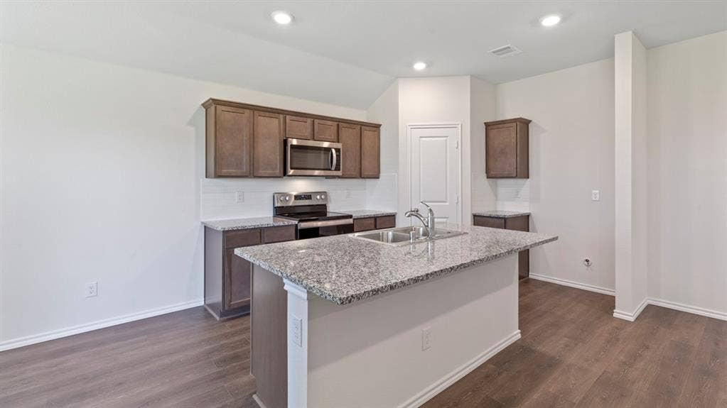 223 Yates Street, Bullard, TX 75757 Kitchen featuring a central island with a double basin sink, granite countertops, wood-finish flooring, and recessed lighting