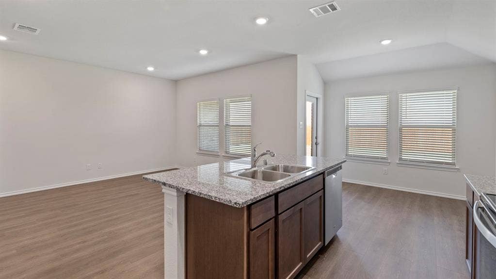 223 Yates Street, Bullard, TX 75757 Kitchen island with granite countertop, double stainless steel sink, integrated dishwasher, dark wood-finish cabinetry, and wood-finish flooring