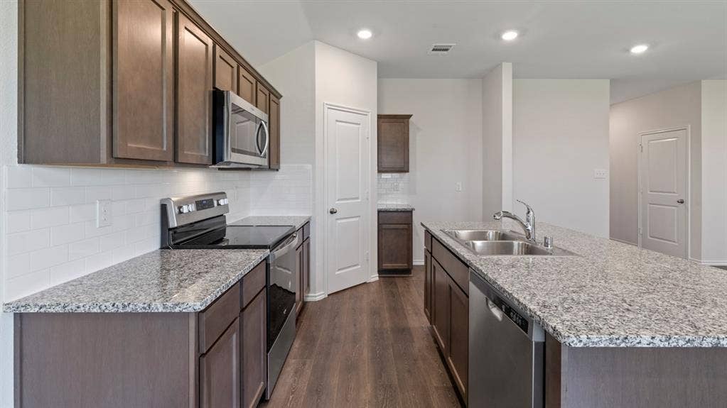 223 Yates Street, Bullard, TX 75757 Kitchen featuring wood-finish flooring, granite countertops, white subway tile backsplash, and stainless steel appliances