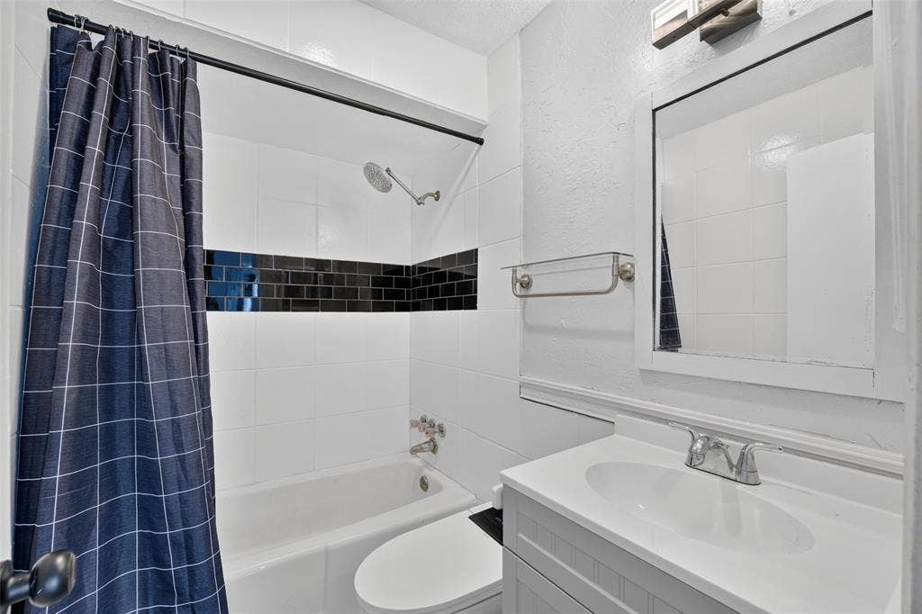 2130 Bowie Drive, Carrollton, TX 75006 Bathroom featuring a vanity with an integrated sink, a framed mirror, and a bathtub with white and black subway tile surround