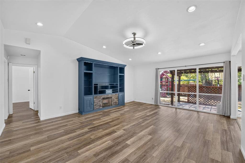 2130 Bowie Drive, Carrollton, TX 75006 Vaulted ceiling, recessed lighting, wood-finish flooring, built-in entertainment center with stone accent, and sliding glass doors