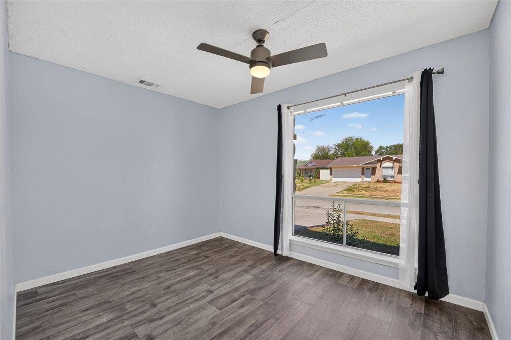 2130 Bowie Drive, Carrollton, TX 75006 Wood-finish flooring, a ceiling fan with integrated lighting, and a large window with white trim