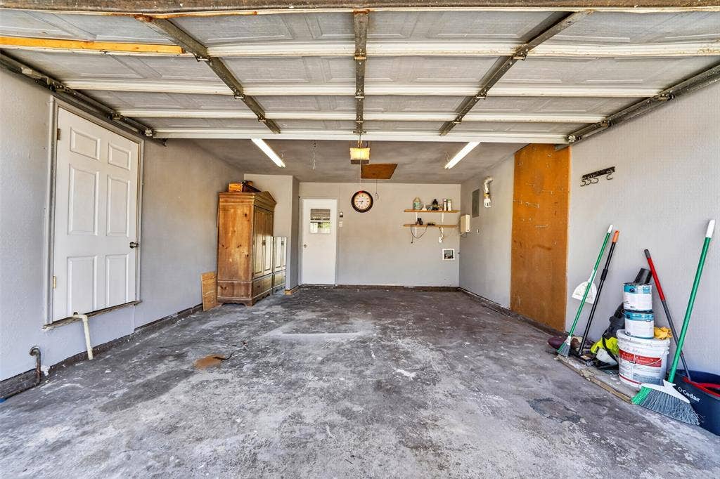 2130 Bowie Drive, Carrollton, TX 75006 Attached garage with concrete flooring, fluorescent lighting, and multiple entry doors