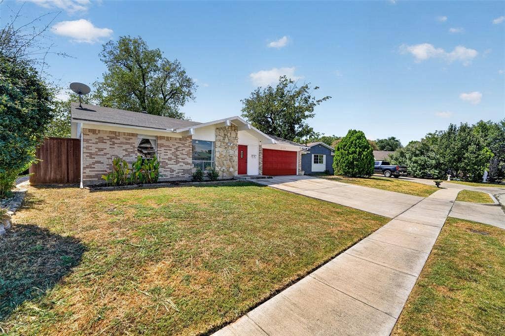 2130 Bowie Drive, Carrollton, TX 75006 Single-story residence featuring a brick and stone facade, a red front door, and an attached garage with a red door