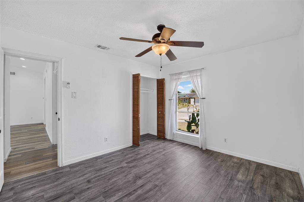 2130 Bowie Drive, Carrollton, TX 75006 Wood-finish flooring throughout, bright window with natural light, integrated ceiling fan with lighting, and bi-fold closet doors