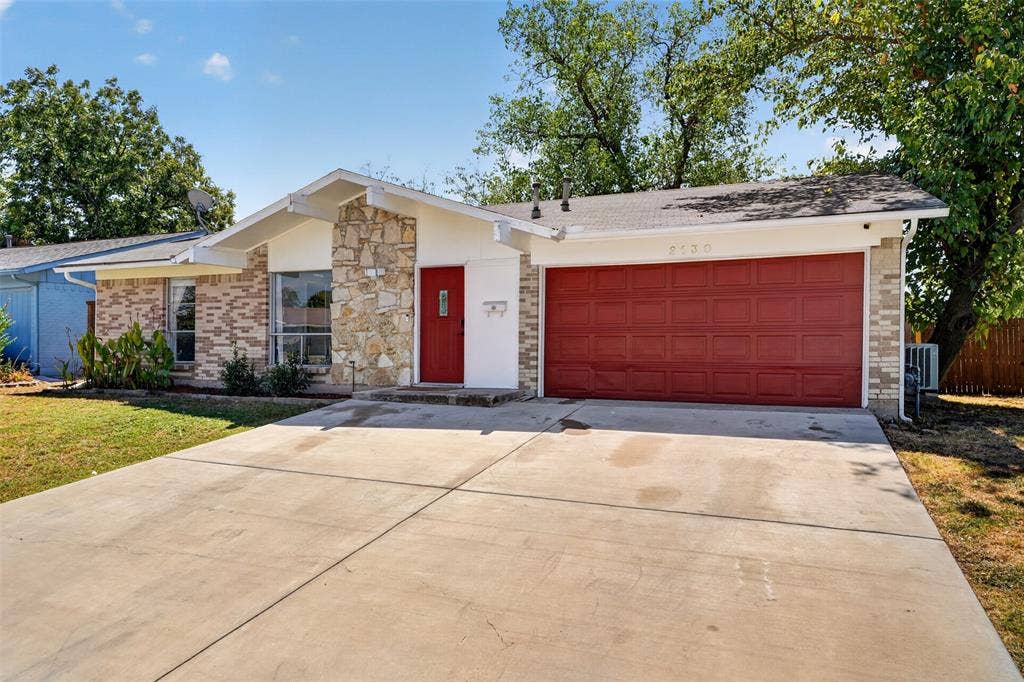 2130 Bowie Drive, Carrollton, TX 75006 Exterior featuring brick and stone veneer, a red front door, a red garage door, and a concrete driveway