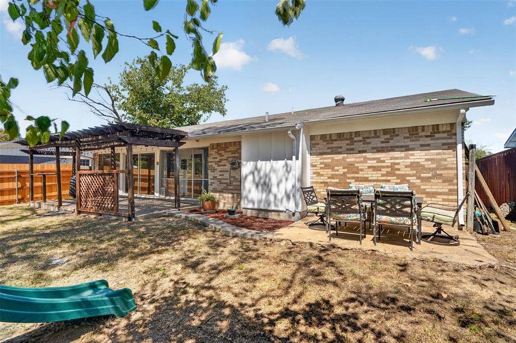 2130 Bowie Drive, Carrollton, TX 75006 Brick exterior with a covered patio area, concrete patio, and a wooden fence