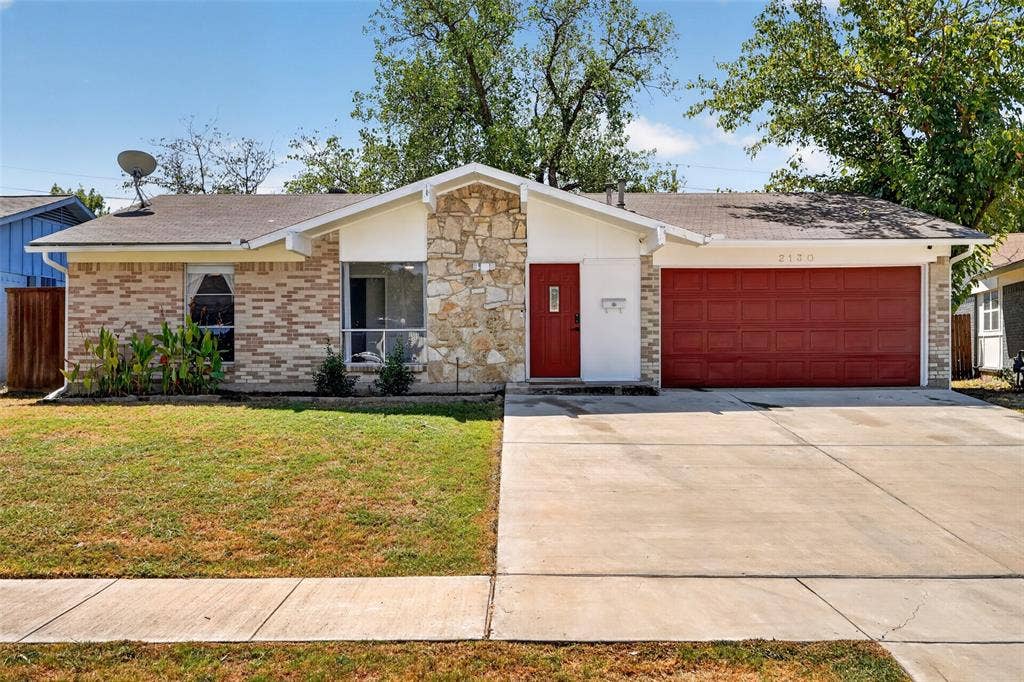 2130 Bowie Drive, Carrollton, TX 75006 Brick and stone exterior featuring a red entry door, a red garage door, and a concrete driveway