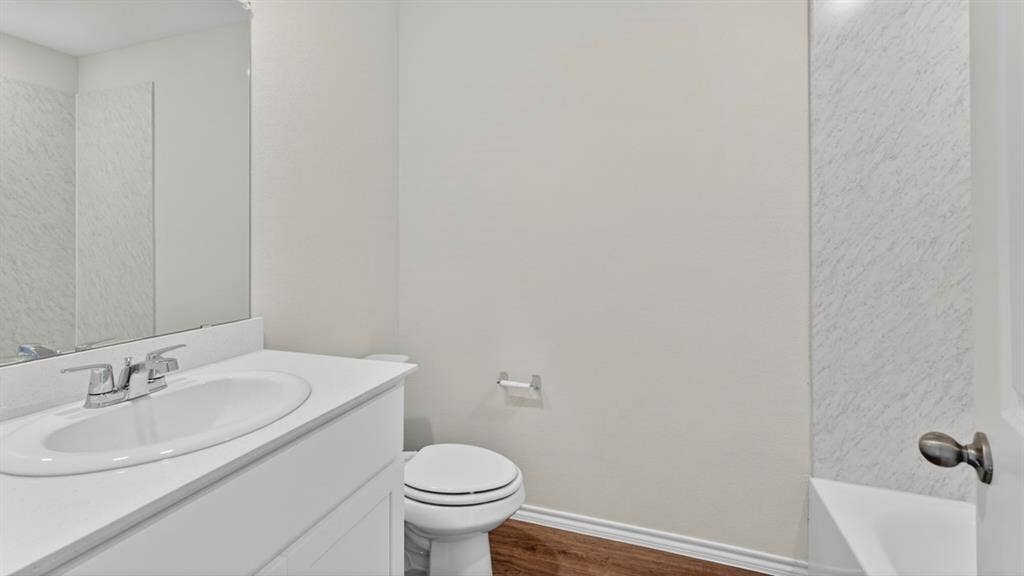 237 Yates Street, Bullard, TX 75757 White vanity with an integrated sink, polished chrome faucet, wood-finish flooring, and wall-mounted mirror