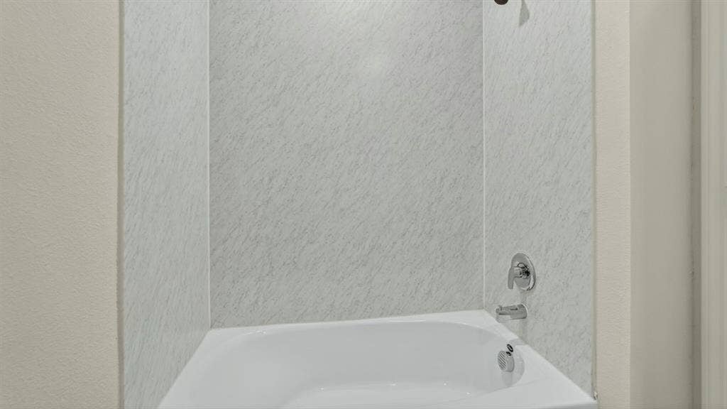 237 Yates Street, Bullard, TX 75757 Bathtub with a shower head, polished chrome fixtures, and a light-toned patterned shower surround