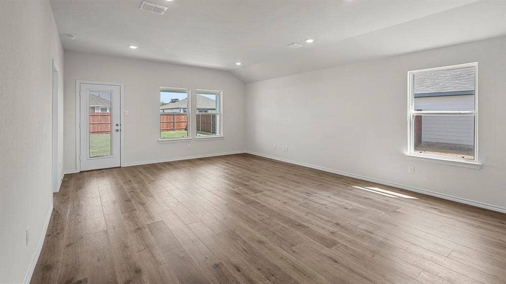 185 Brooks Street, Bullard, TX 75757 Spacious room featuring wood-finish flooring, multiple windows, a glass-panel door, recessed lighting, and a vaulted ceiling
