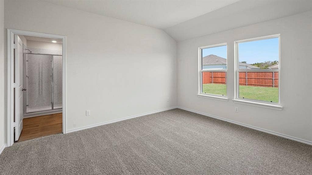 185 Brooks Street, Bullard, TX 75757 Neutral-toned carpeting, white walls, two double-hung windows, and a vaulted ceiling