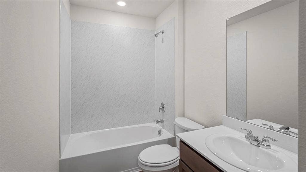 185 Brooks Street, Bullard, TX 75757 White bathtub with shower, white wall paneling, vanity with integrated sink, chrome-finish faucet, and an overhead lighting fixture