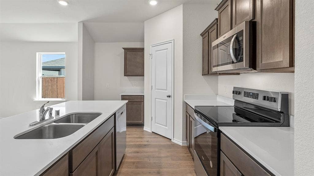 185 Brooks Street, Bullard, TX 75757 Kitchen featuring an undermount double basin sink, white countertops, wood-finish flooring, dark wood-finish cabinetry, and stainless steel appliances