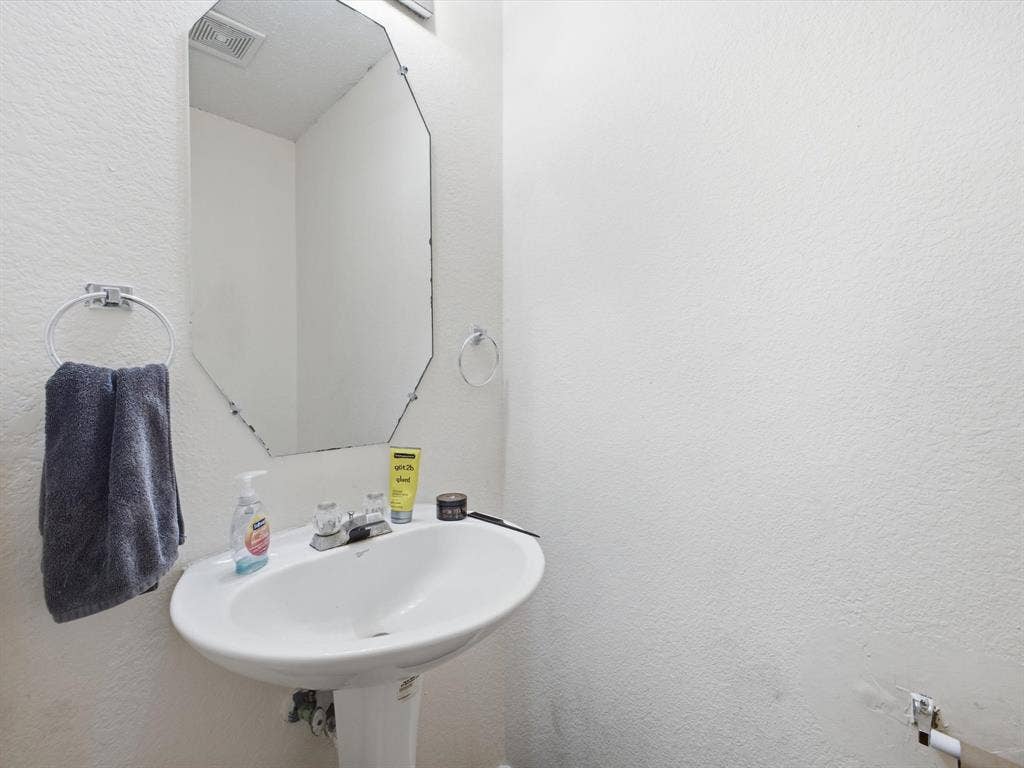 2001 Waleska Plaza, Dallas, TX 75211 Pedestal sink with chrome faucet, octagonal wall mirror, and chrome towel rings