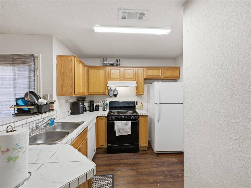 2001 Waleska Plaza, Dallas, TX 75211 Kitchen featuring wood-finish cabinetry, tile countertops, and a dual basin stainless steel sink